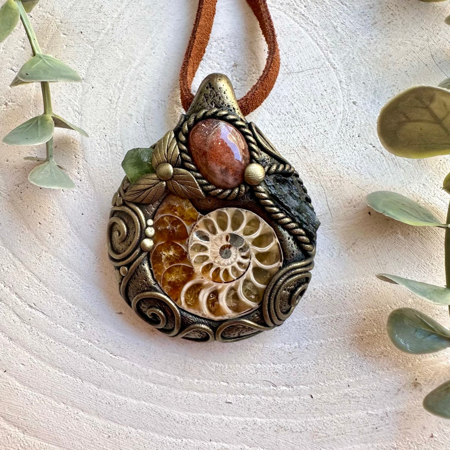 Handmade Ammonite necklace featuring Sunstone, Moldavite and Peridot, a one of a kind unisex gemstone jewelry piece combining an ancient natural fossil with warm and vibrant green crystals.