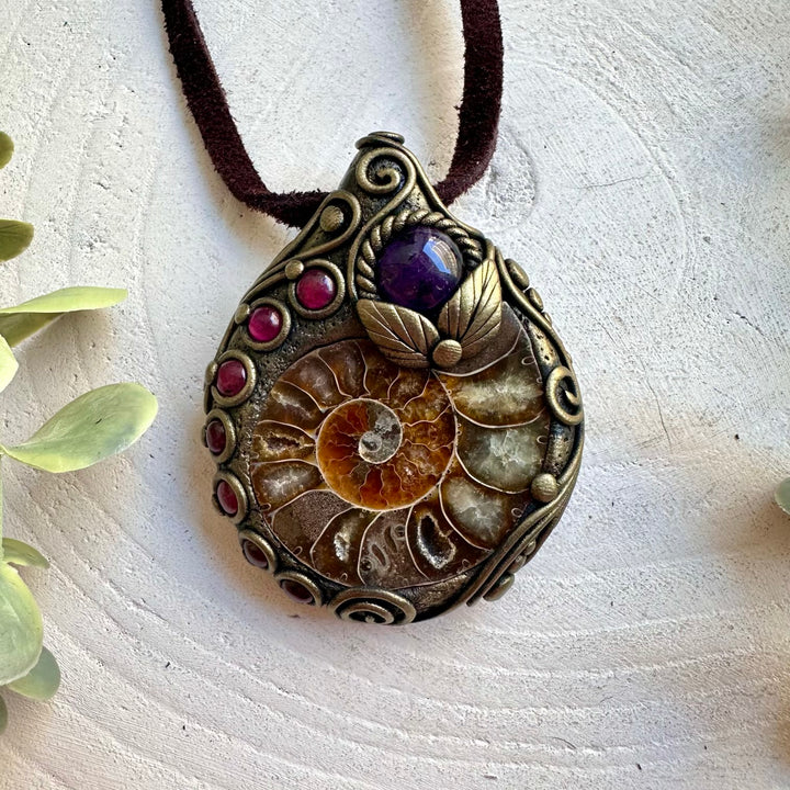 Unique crystal pendant featuring the natural spiral of Ammonite with purple and red gemstone accents.