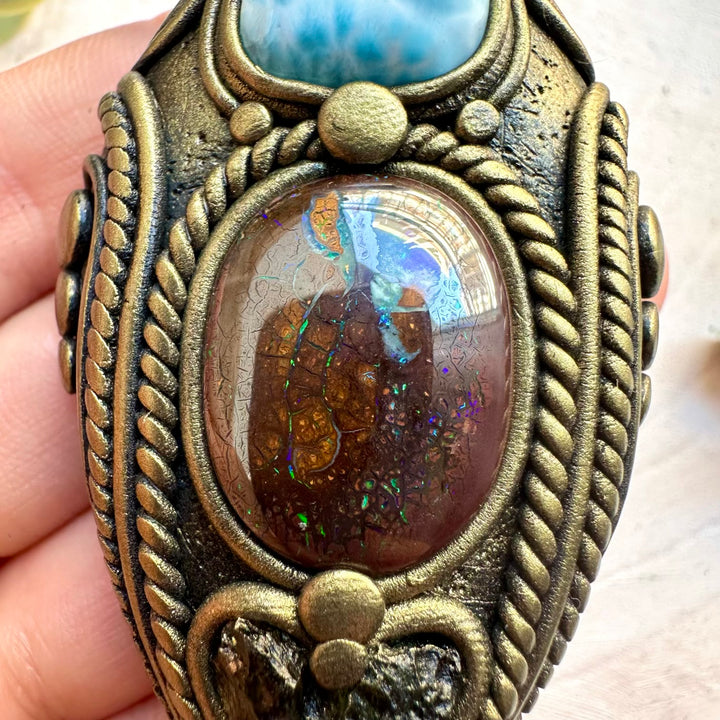 Close up of opal larimar and moldavite crystal pendant