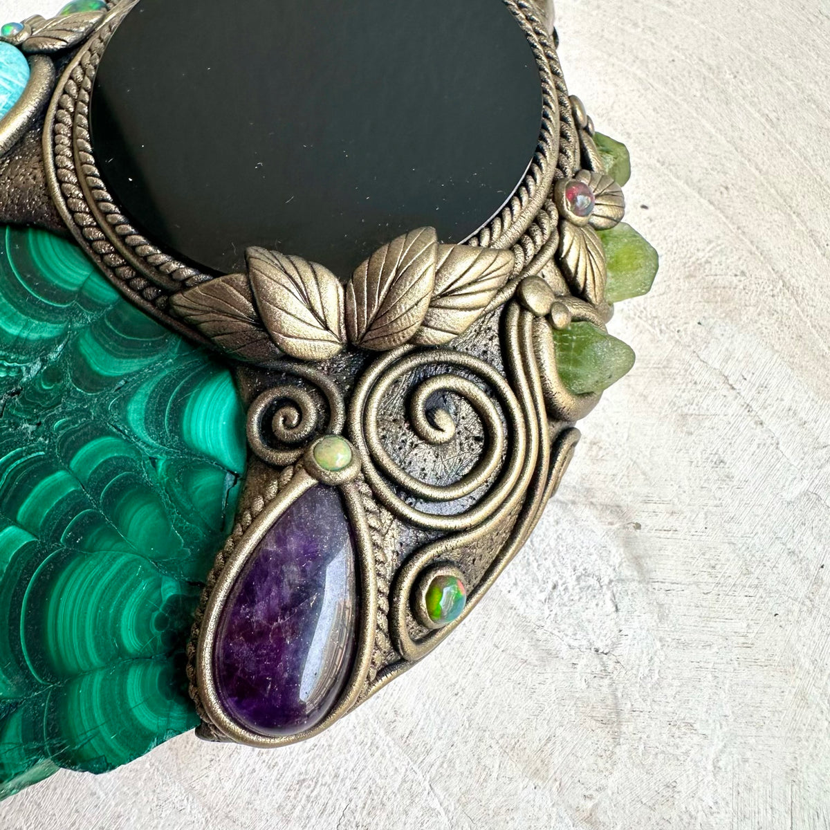 Black Obsidian mirror framed with natural Malachite and accented by Amazonite and purple Amethyst in unique crystal wall art.