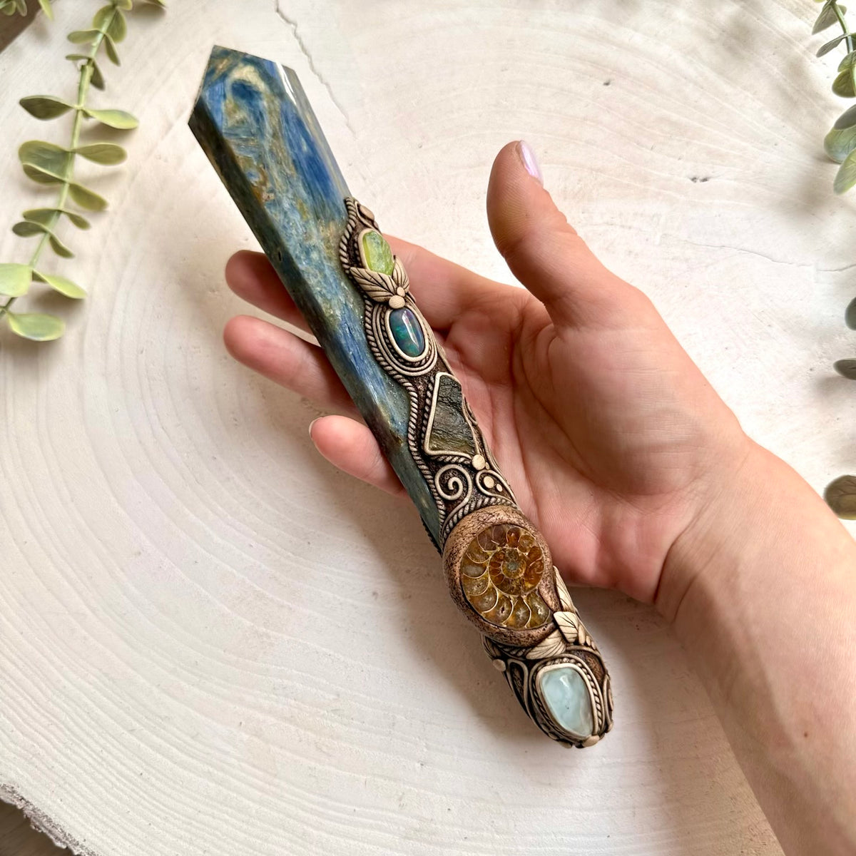 Natural Blue Kyanite paired with an ancient Ammonite, pale Aquamarine and vivid green Moldavite in a unique crystal wand.