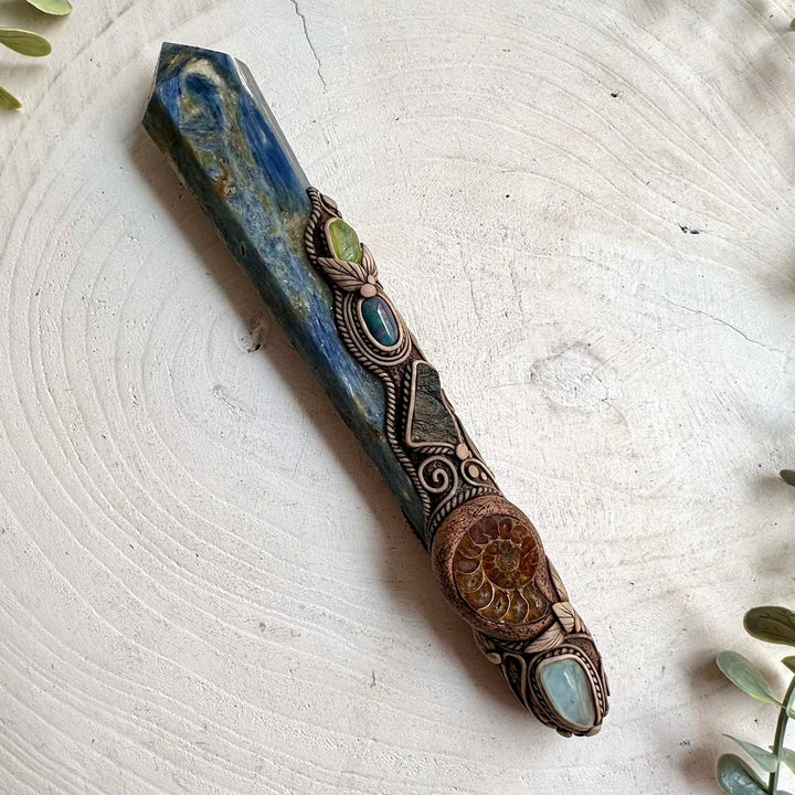 Deep blue Kyanite contrasts with pale Aquamarine and green Peridot in this unique handmade crystal wand with Black Ethiopian Opal.