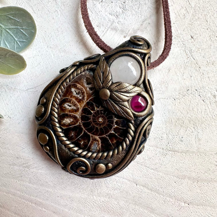 Handmade gemstone jewelry featuring Ammonite, Clear Quartz, and Rhodolite Garnet for chakra healing and spiritual balance.