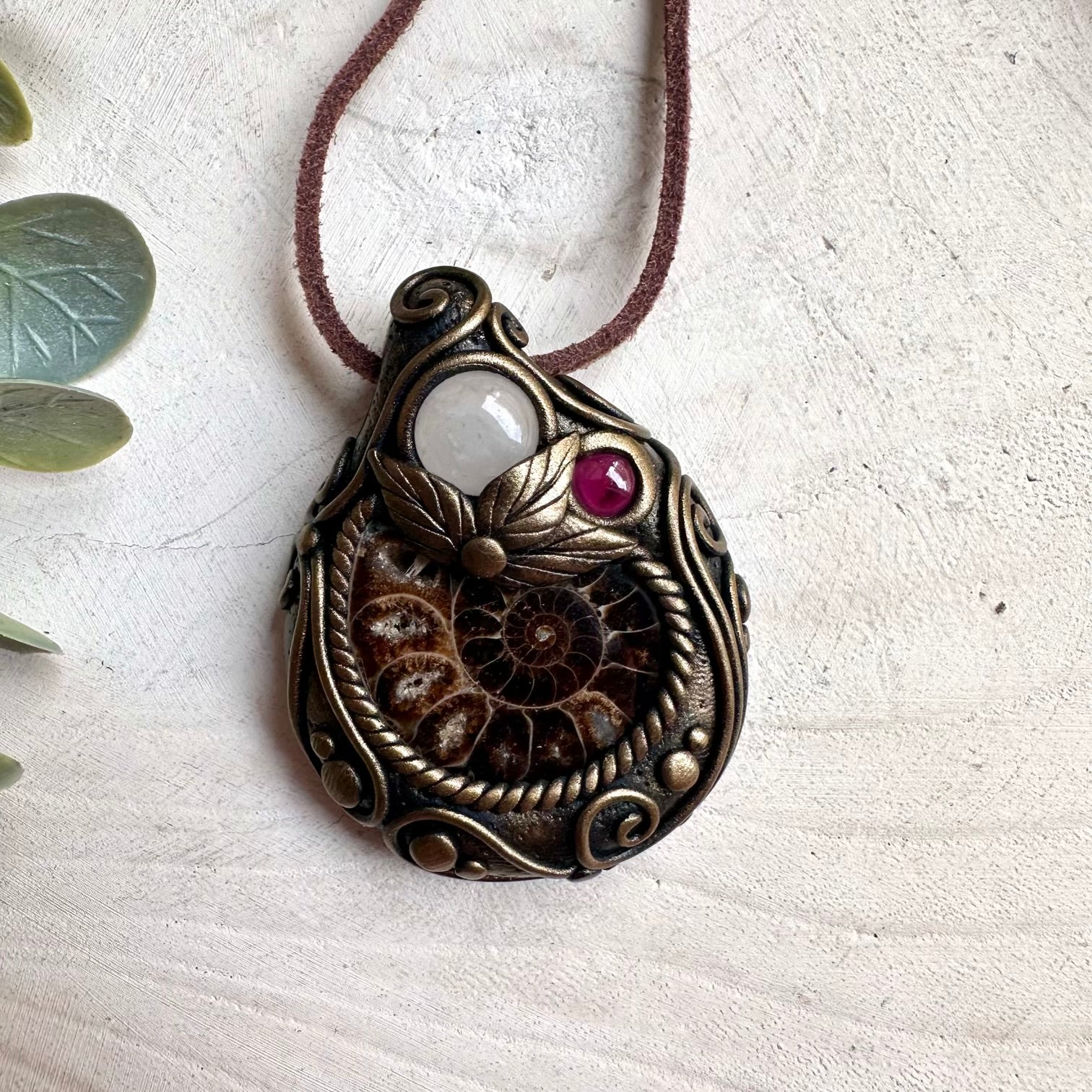 Spiritual jewelry necklace featuring Ammonite fossil, Clear Quartz, and Rhodolite Garnet for healing and transformation.