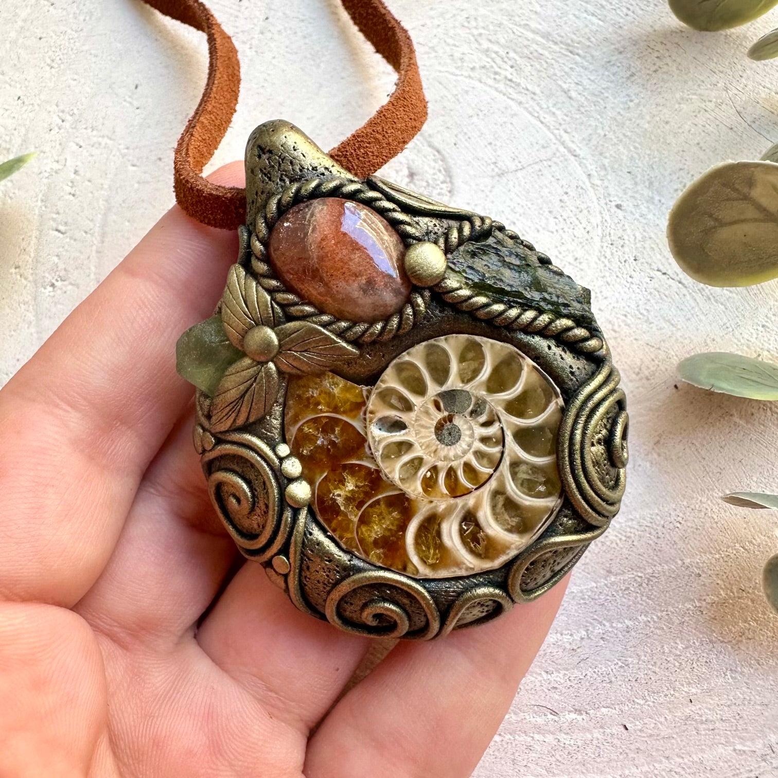 Handmade Ammonite necklace featuring Sunstone, Moldavite and Peridot, a one of a kind unisex gemstone jewelry piece combining an ancient natural fossil with warm and vibrant green crystals. Artisan spiritual jewelry crafted with genuine natural materials, inspired by transformation, confidence, renewal and personal growth.