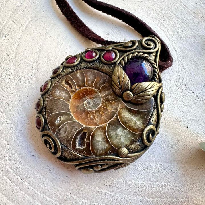 Natural gemstone pendant featuring Amethyst and Rhodolite Garnet alongside a detailed Ammonite fossil.