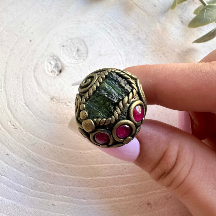 Artisan ring showcasing green Moldavite with a deep red Rhodolite Garnet gemstone.