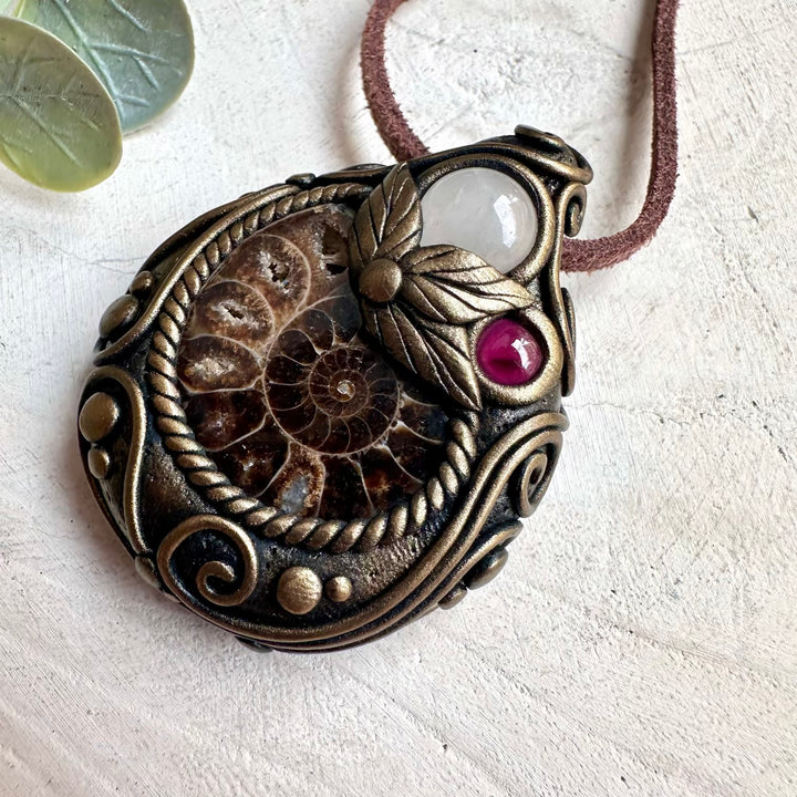 Healing crystal necklace handcrafted with natural Ammonite, Clear Quartz, and Rhodolite Garnet gemstones.