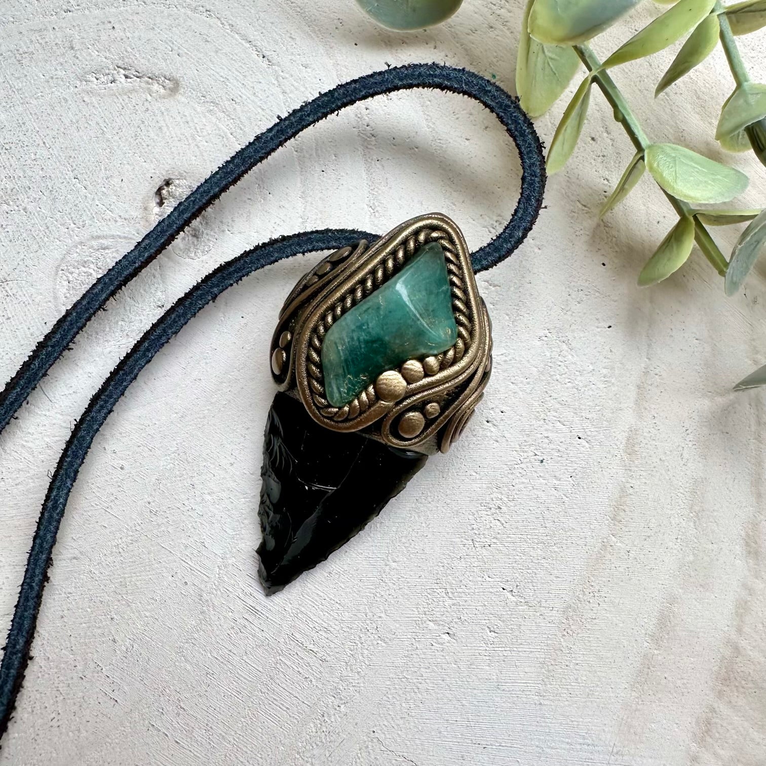 Obsidian arrowhead paired with emerald in a necklace