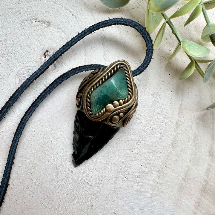 Obsidian arrowhead paired with emerald in a necklace