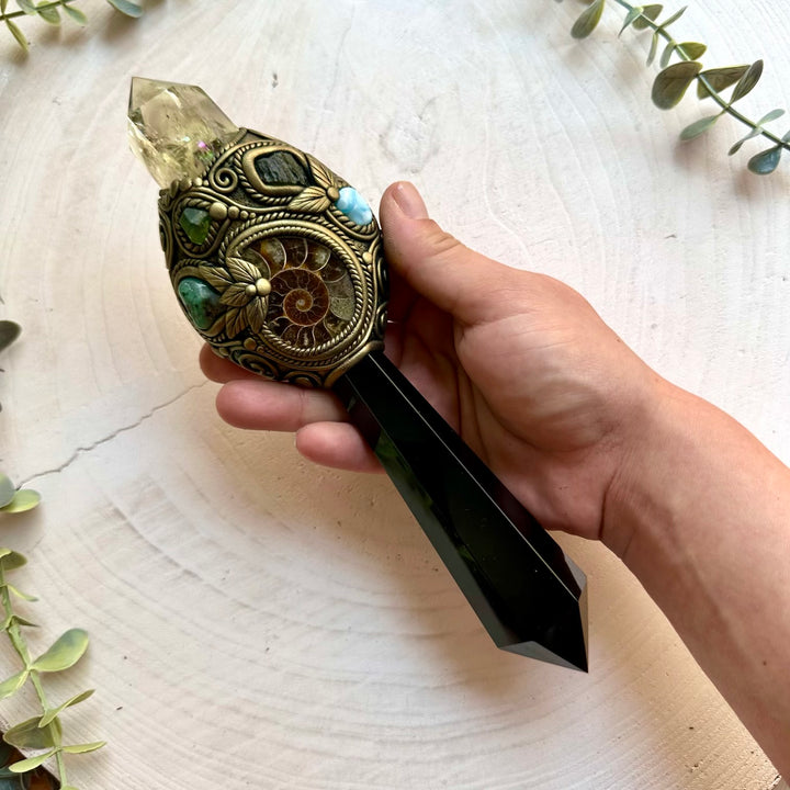 Carefully handcrafted with Black Obsidian, Citrine, Ammonite, Emerald, Peridot, Moldavite and Larimar, this unique wand blends raw and polished natural gemstones into a meaningful work of art.