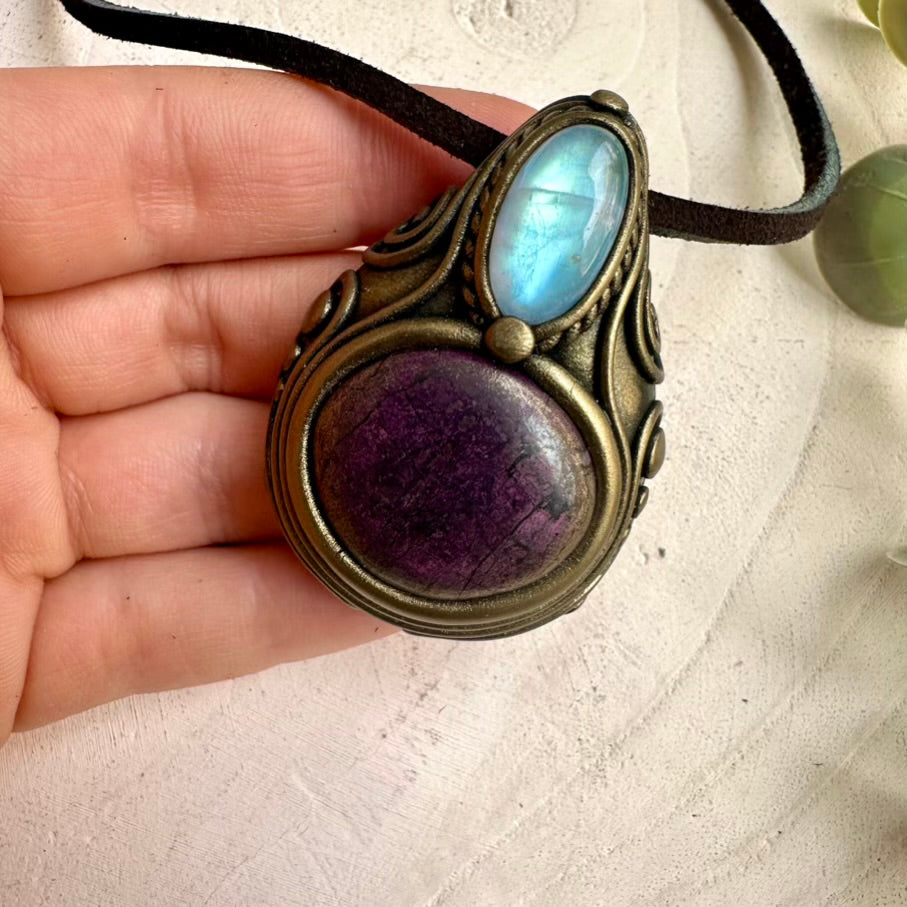 Close up of purpurite and rainbow moonstone crystal pendant