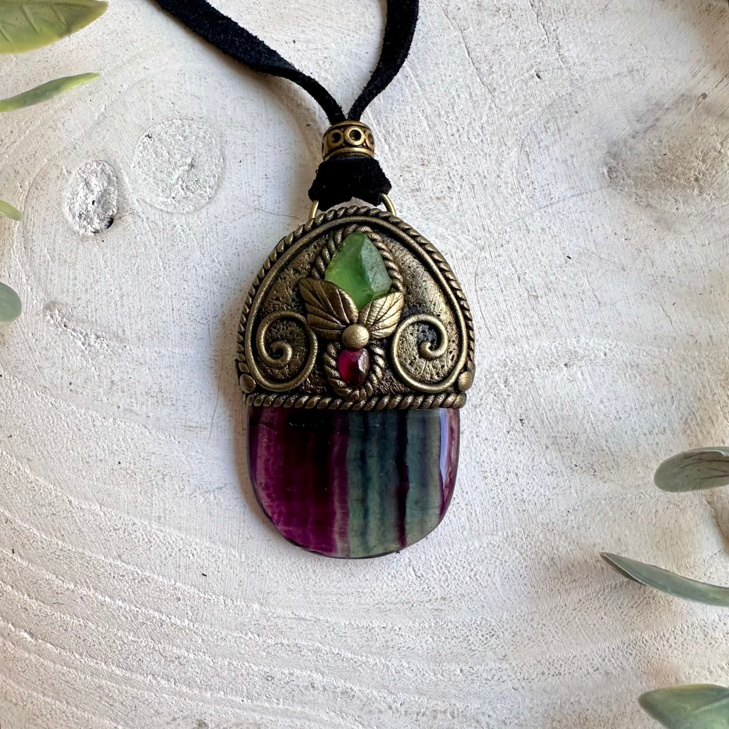 Handmade Rainbow Fluorite pendant necklace featuring Raw Peridot and Rhodolite Garnet, a one of a kind healing crystal jewelry piece combining naturally colorful Fluorite with vibrant green and deep red gemstones. One of a kind spiritual jewelry inspired by clarity, renewal, confidence, courage and personal transformation.