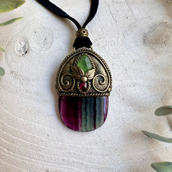 Handmade Rainbow Fluorite pendant necklace featuring Raw Peridot and Rhodolite Garnet, a one of a kind healing crystal jewelry piece combining naturally colorful Fluorite with vibrant green and deep red gemstones. One of a kind spiritual jewelry inspired by clarity, renewal, confidence, courage and personal transformation.