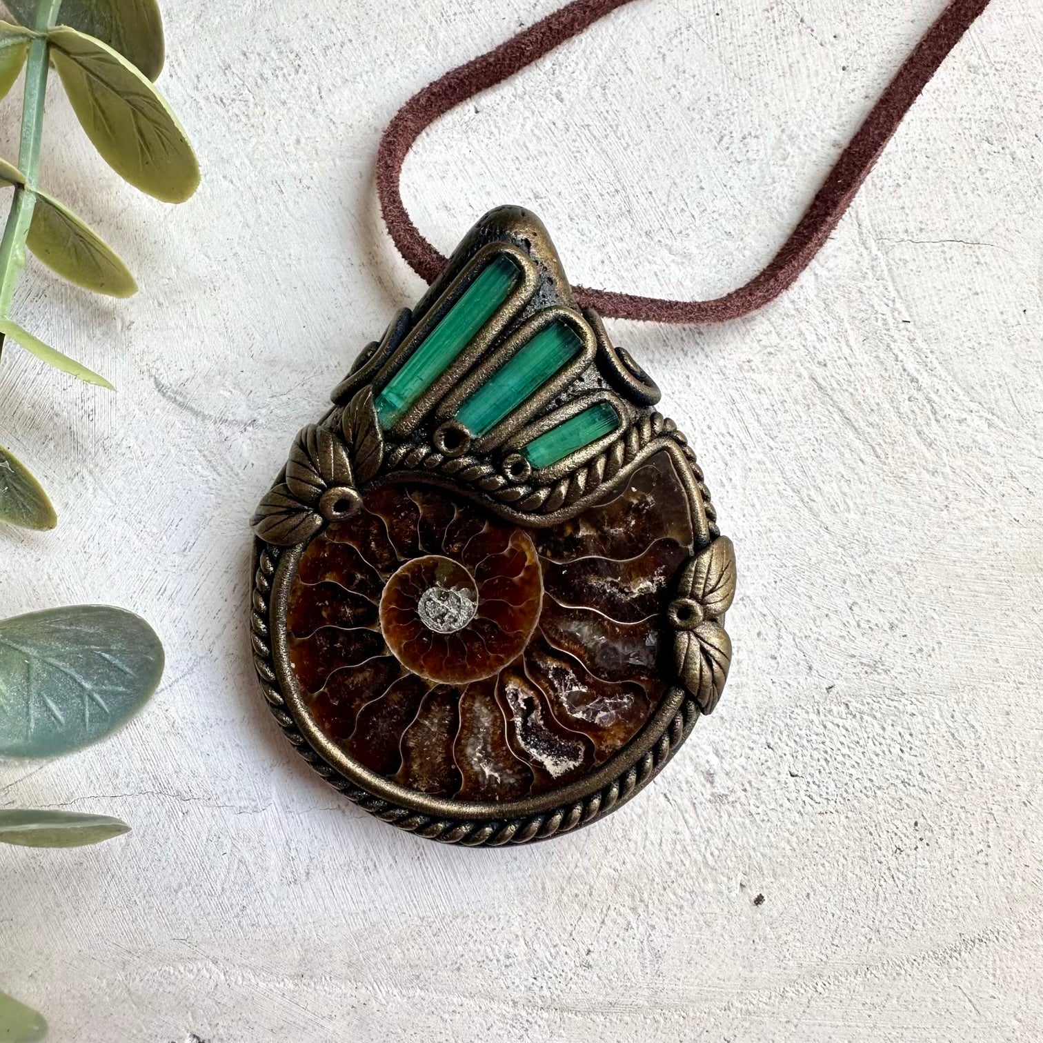 Raw healing crystal necklace featuring green tourmaline stones and ammonite fossil pendant