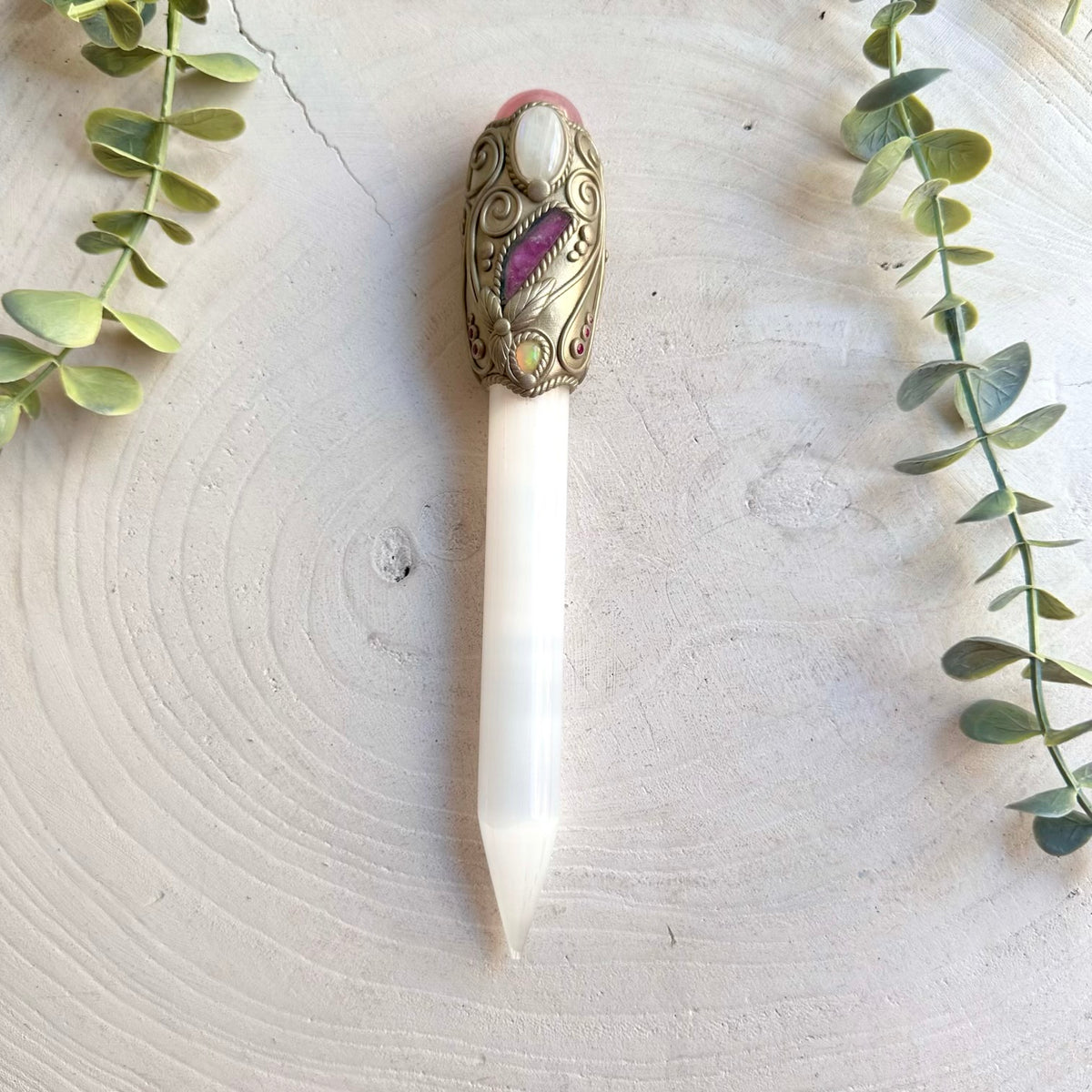The luminous Selenite wand is beautifully complemented by soft Rose Quartz, mystical Moonstone, colorful Watermelon Tourmaline, glowing Ethiopian Opal and vibrant Ruby, creating an enchanting spiritual crystal tool filled with symbolic energy.
