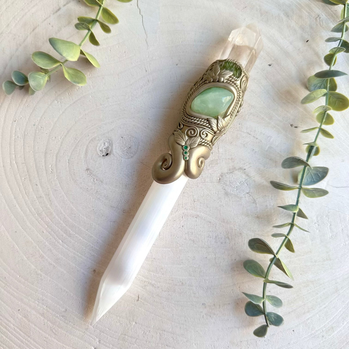 The luminous Selenite wand is beautifully complemented by Clear Quartz, soft green Prehnite, transformative Moldavite and rich green Emerald, creating an enchanting spiritual crystal tool inspired by clarity, intuition, renewal, transformation and heart-centered energy.